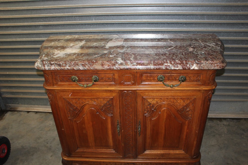 A carved French provincial oak sideboard featuring two drawers, two cabinet doors, carved geometric and floral motifs, cabriole feet, and a thick grey veined marble top. View VI