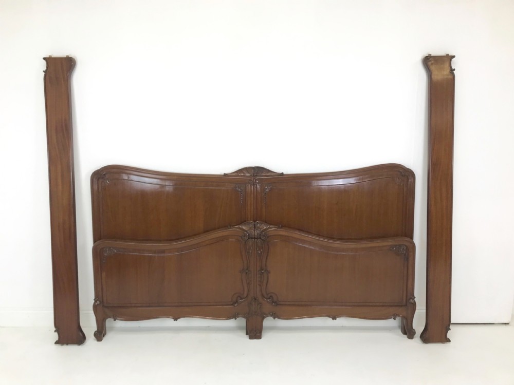 A carved mahogany king size bed frame featuring an arched headboard and matching footboard with intricate foliate detailing and cabriole feet. View V