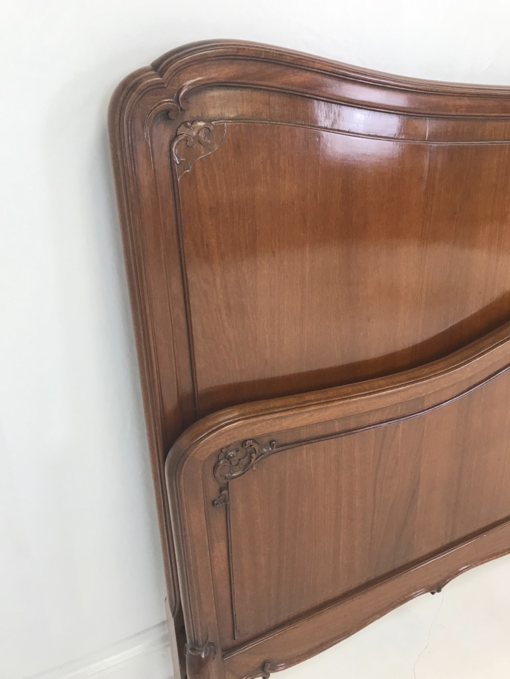 A carved mahogany king size bed frame featuring an arched headboard and matching footboard with intricate foliate detailing and cabriole feet. View VI