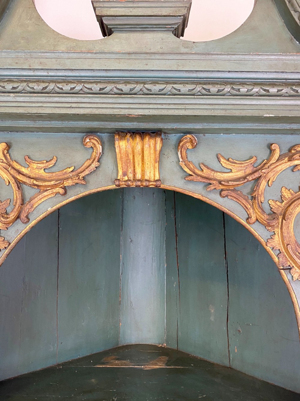 An 18th-century floor-standing teal green open corner cupboard featuring gold leaf detailing, fluted pilasters, and a broken swan-neck pediment. View V