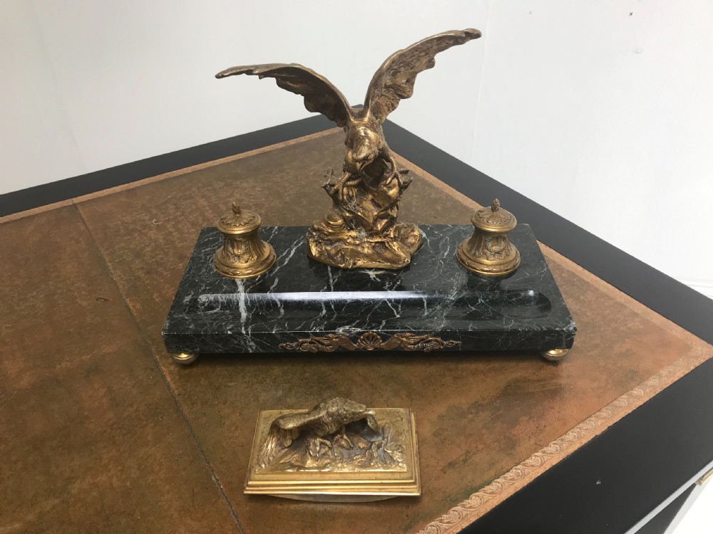 A French gilt bronze eagle sculpture mounted on a black marble base with two lidded ink pots, a pen recess, and an accompanying rocker blotter.