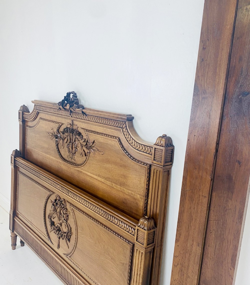 Carved walnut wood bed headboard and footboard set featuring classical ribbon and swag relief details. View VI