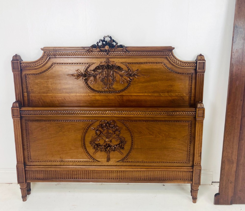 Carved walnut wood bed headboard and footboard set featuring classical ribbon and swag relief details. View IX