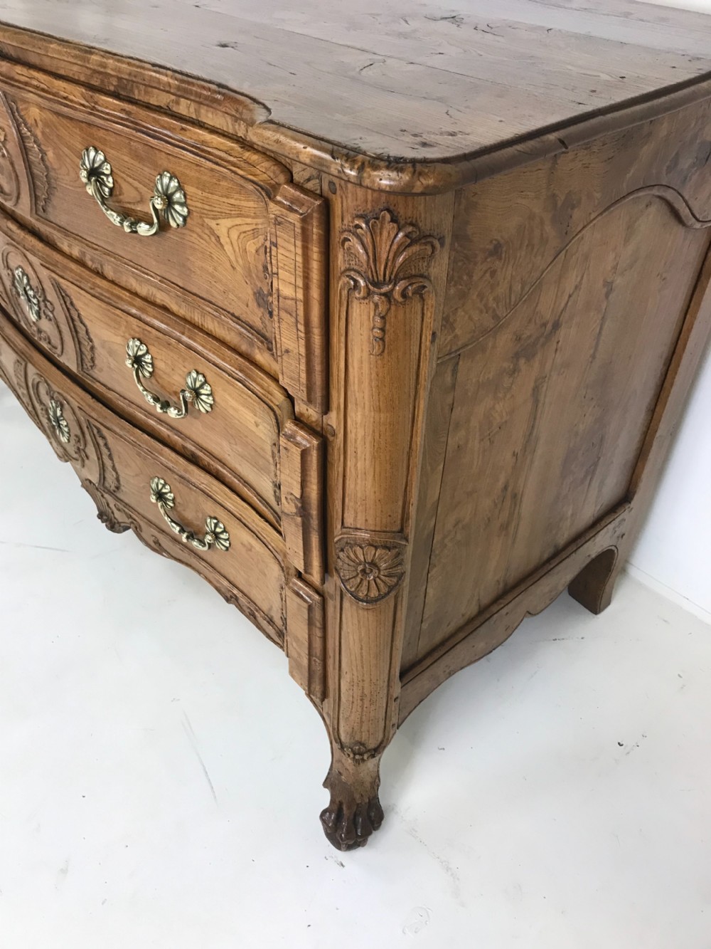 An 18th-century French provincial burr ash commode featuring three drawers with carved rocaille motifs, original brass handles, and cabriole legs. View VI