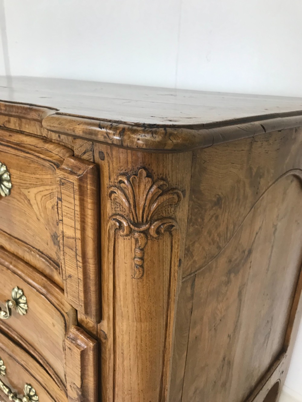An 18th-century French provincial burr ash commode featuring three drawers with carved rocaille motifs, original brass handles, and cabriole legs. View VIII