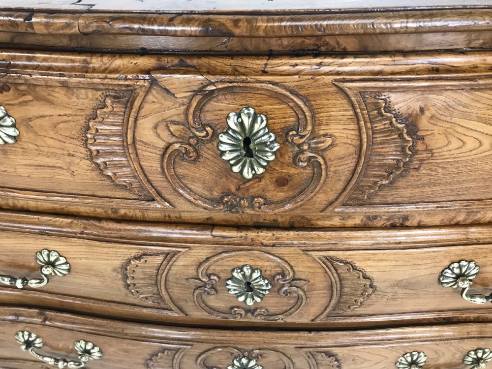 An 18th-century French provincial burr ash commode featuring three drawers with carved rocaille motifs, original brass handles, and cabriole legs. View IX