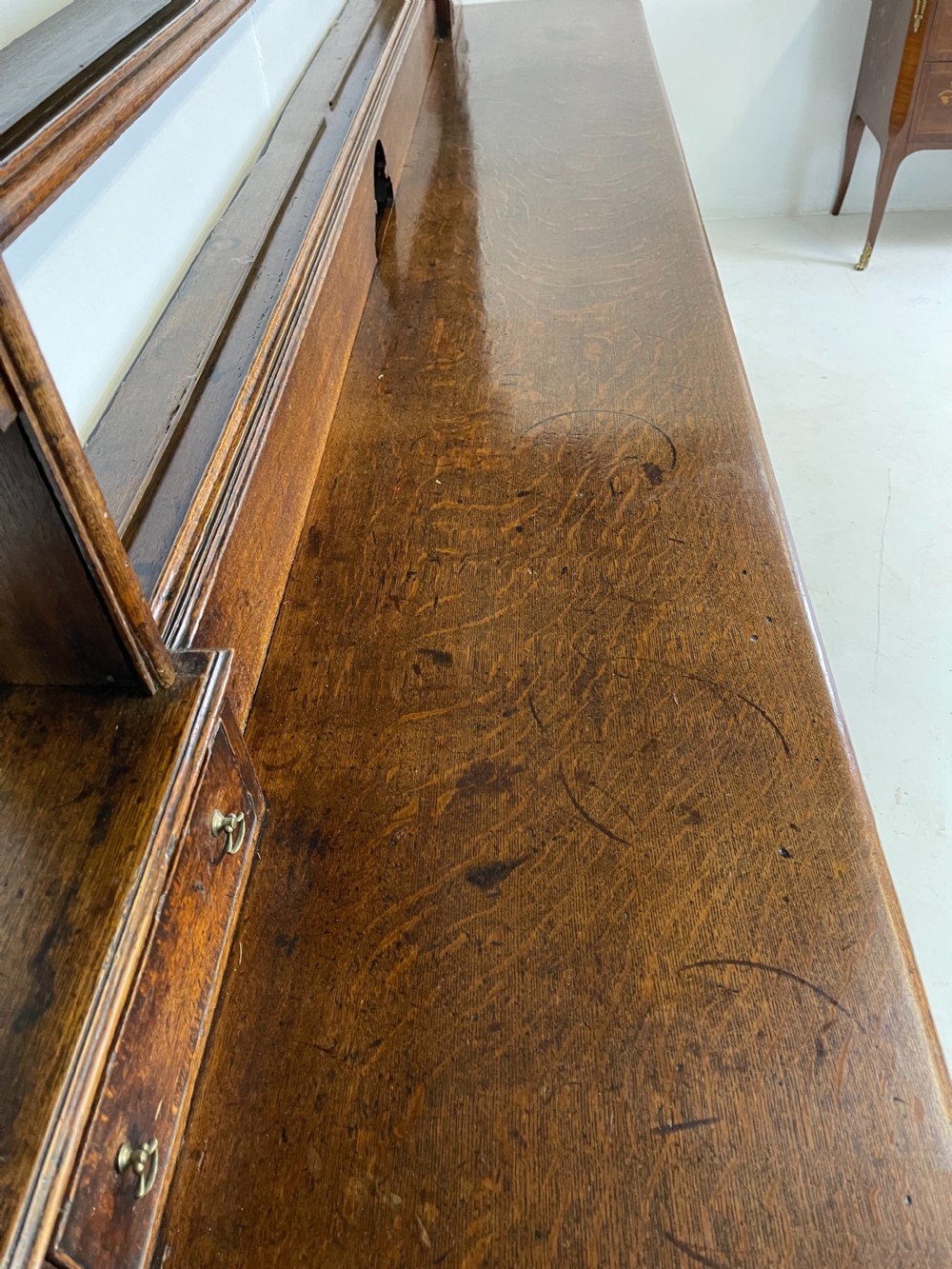 A large dark oak dresser featuring a multi-tiered open plate rack top above a wide base with drawers and panelled cupboard doors. View V