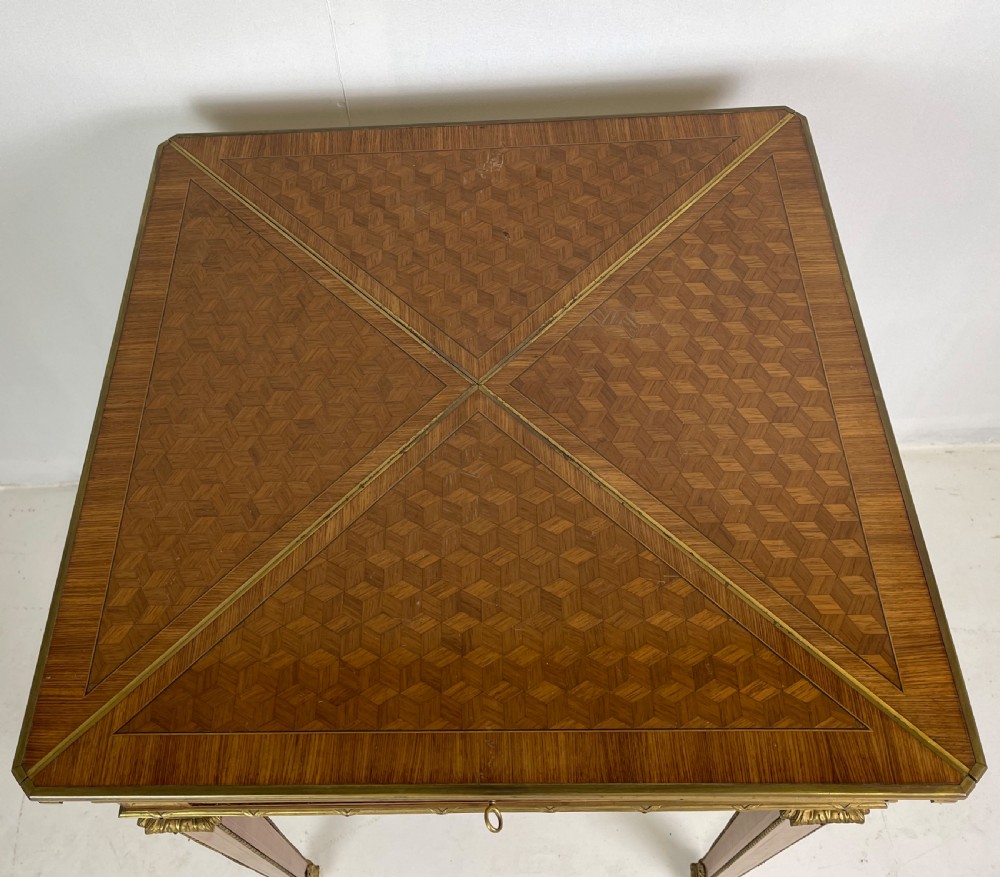 A square French Louis XVI style parquetry envelope card table featuring detailed gilt-bronze mounts and tapered legs. View VII