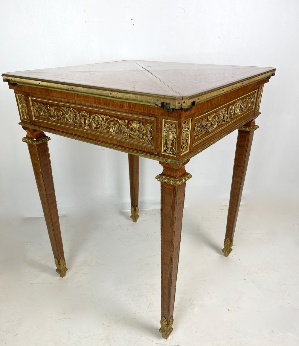 A square French Louis XVI style parquetry envelope card table featuring detailed gilt-bronze mounts and tapered legs. View IX