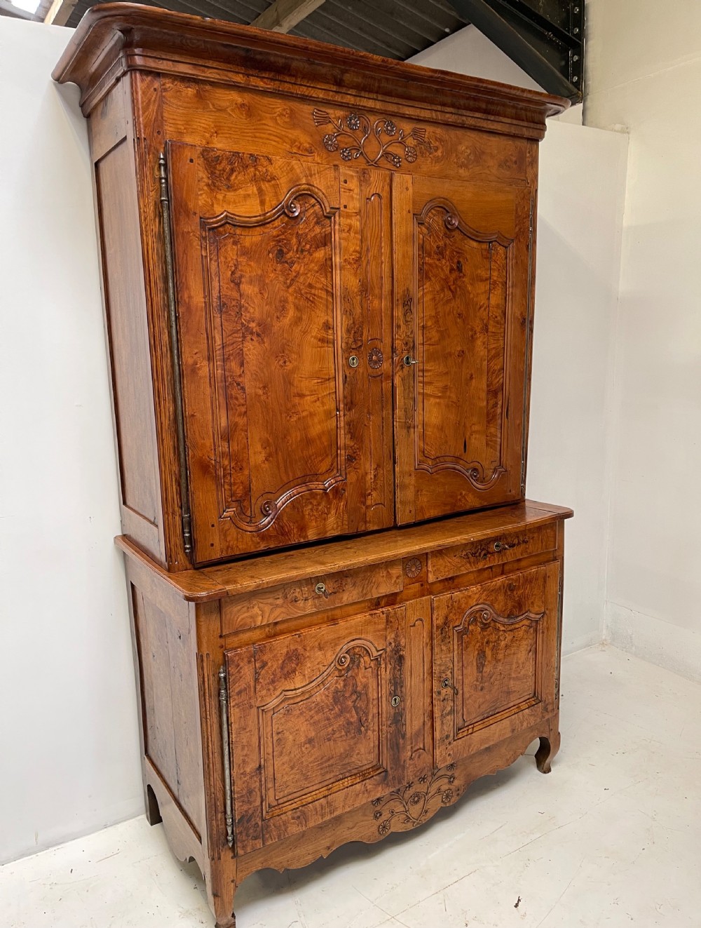 An antique two-piece French walnut cabinet featuring carved floral crests, molded panel doors, two drawers, and short cabriole feet. View II