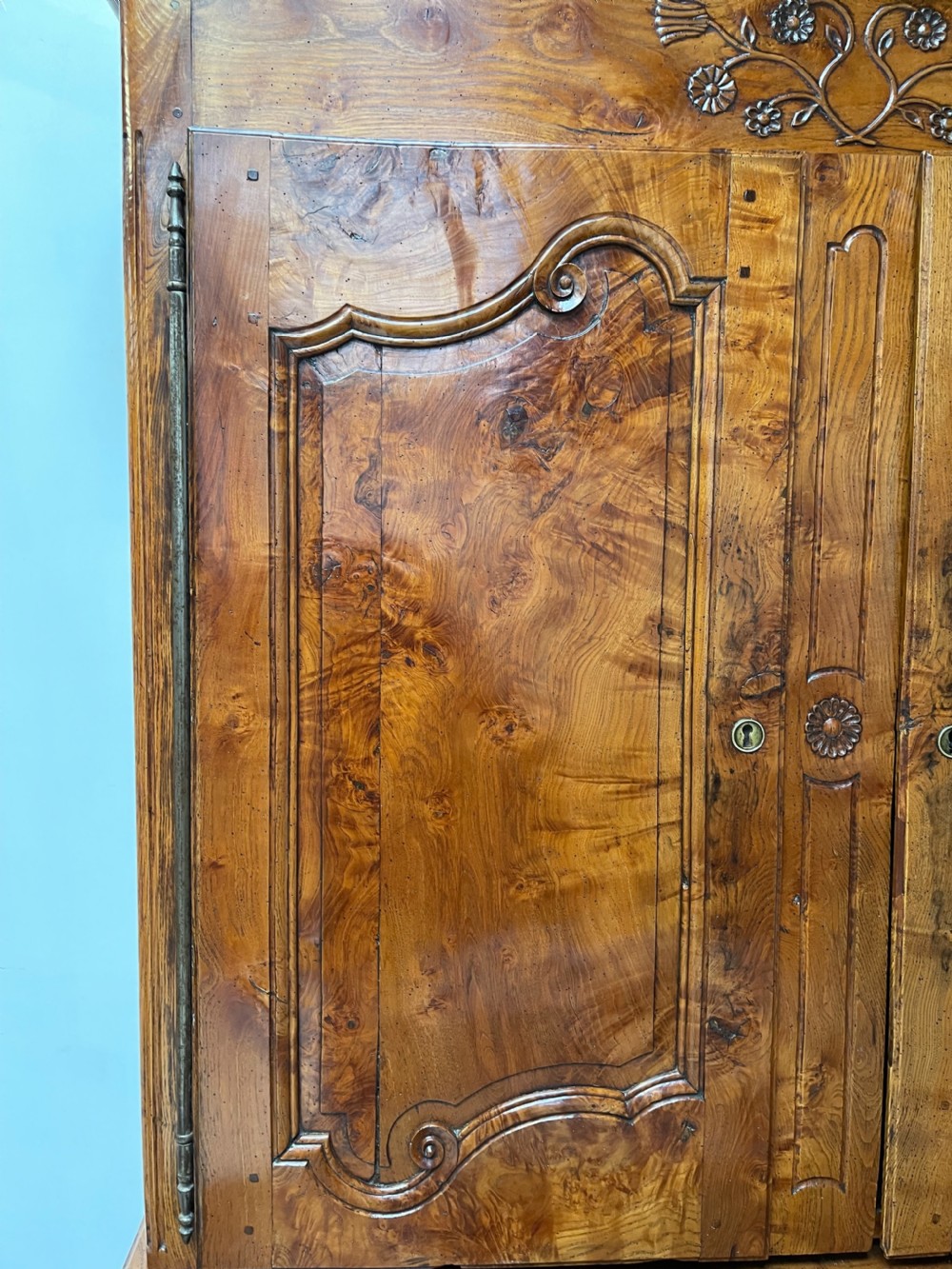 An antique two-piece French walnut cabinet featuring carved floral crests, molded panel doors, two drawers, and short cabriole feet. View III