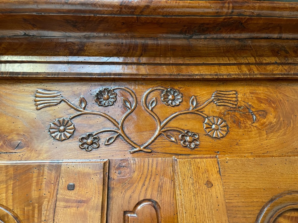 An antique two-piece French walnut cabinet featuring carved floral crests, molded panel doors, two drawers, and short cabriole feet. View IV
