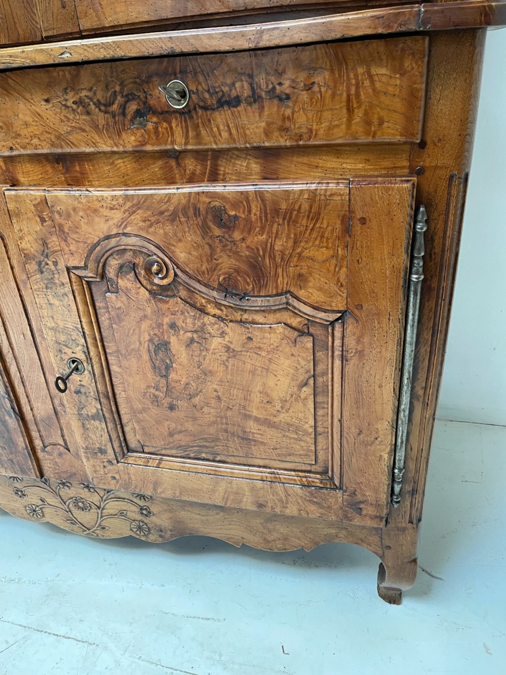 An antique two-piece French walnut cabinet featuring carved floral crests, molded panel doors, two drawers, and short cabriole feet. View VI
