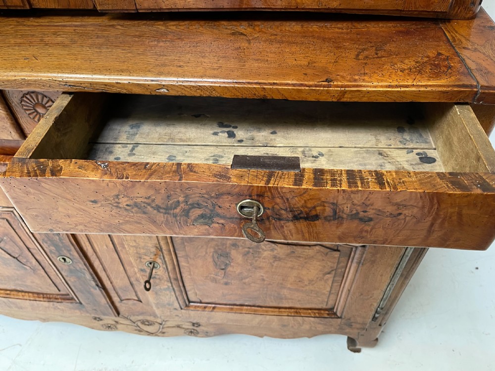 An antique two-piece French walnut cabinet featuring carved floral crests, molded panel doors, two drawers, and short cabriole feet. View VIII