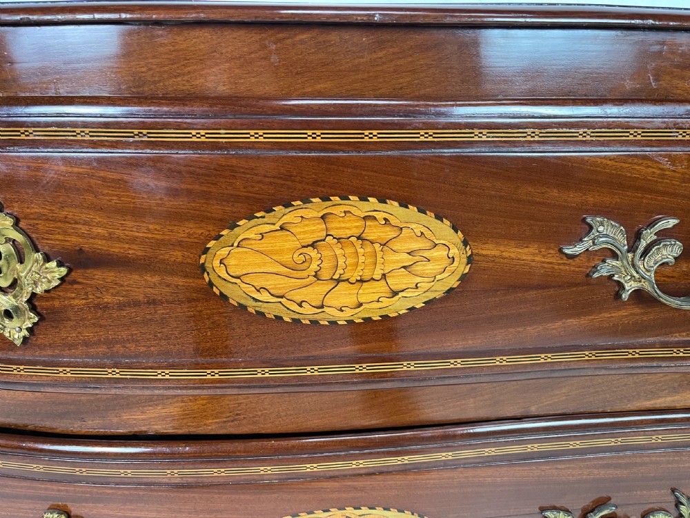 An 18th-century French walnut commode featuring three drawers with elaborate fruitwood marquetry inlays, cast brass escutcheons, and curved cabriole legs. View V
