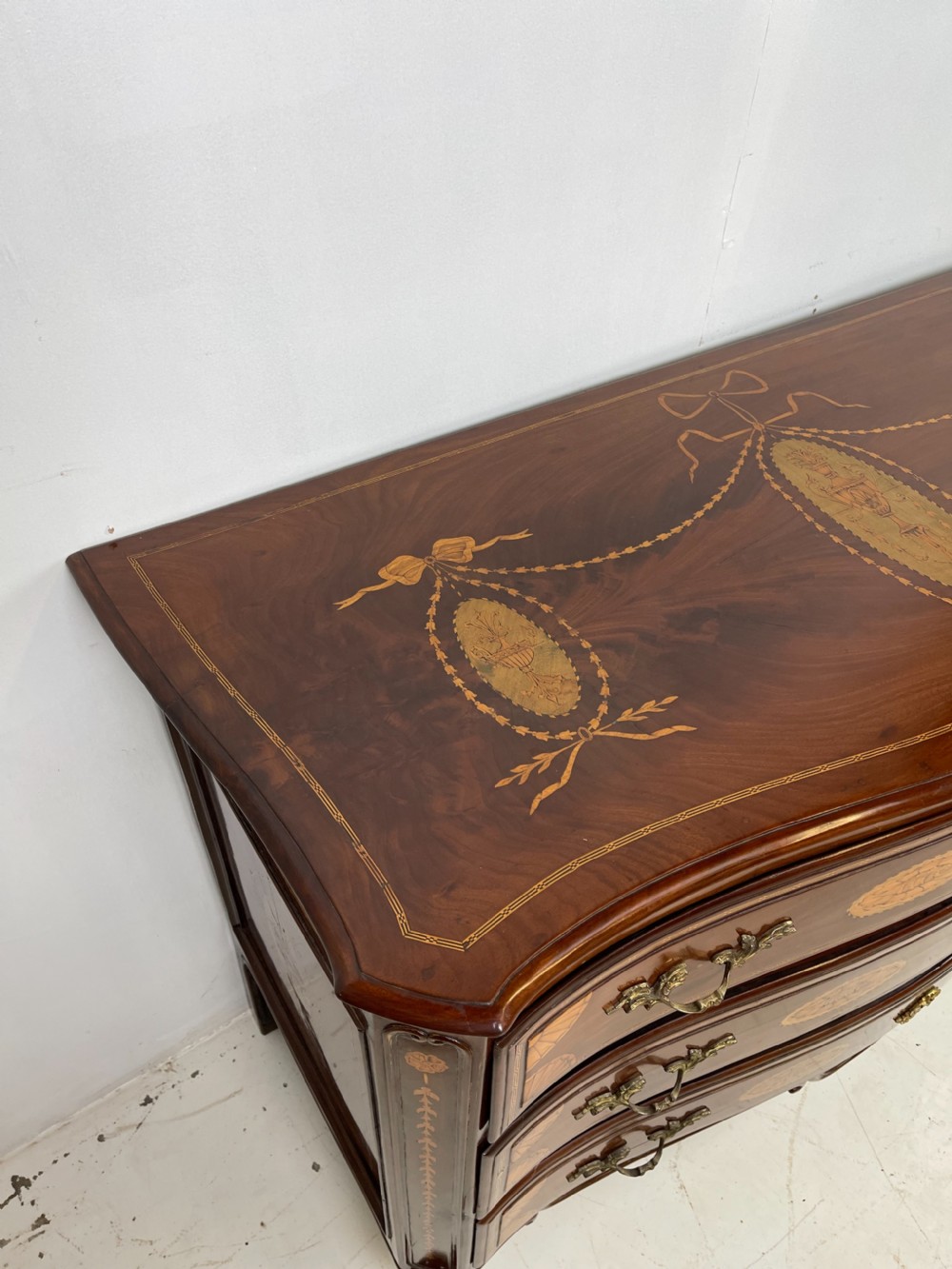 An 18th-century French walnut commode featuring three drawers with elaborate fruitwood marquetry inlays, cast brass escutcheons, and curved cabriole legs. View IX