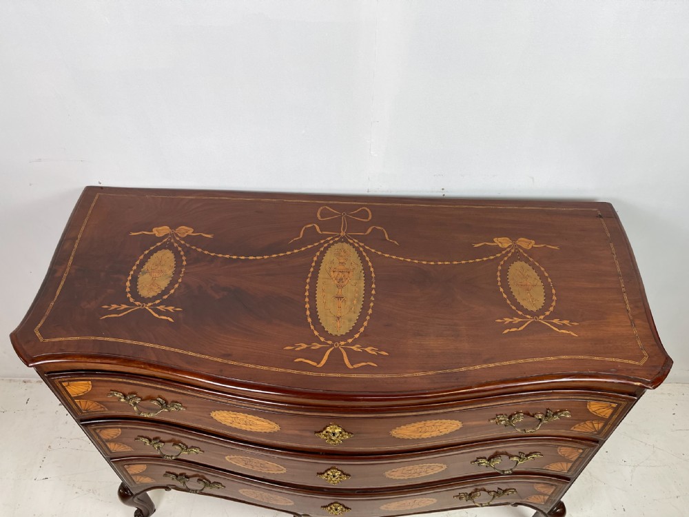 An 18th-century French walnut commode featuring three drawers with elaborate fruitwood marquetry inlays, cast brass escutcheons, and curved cabriole legs. View X