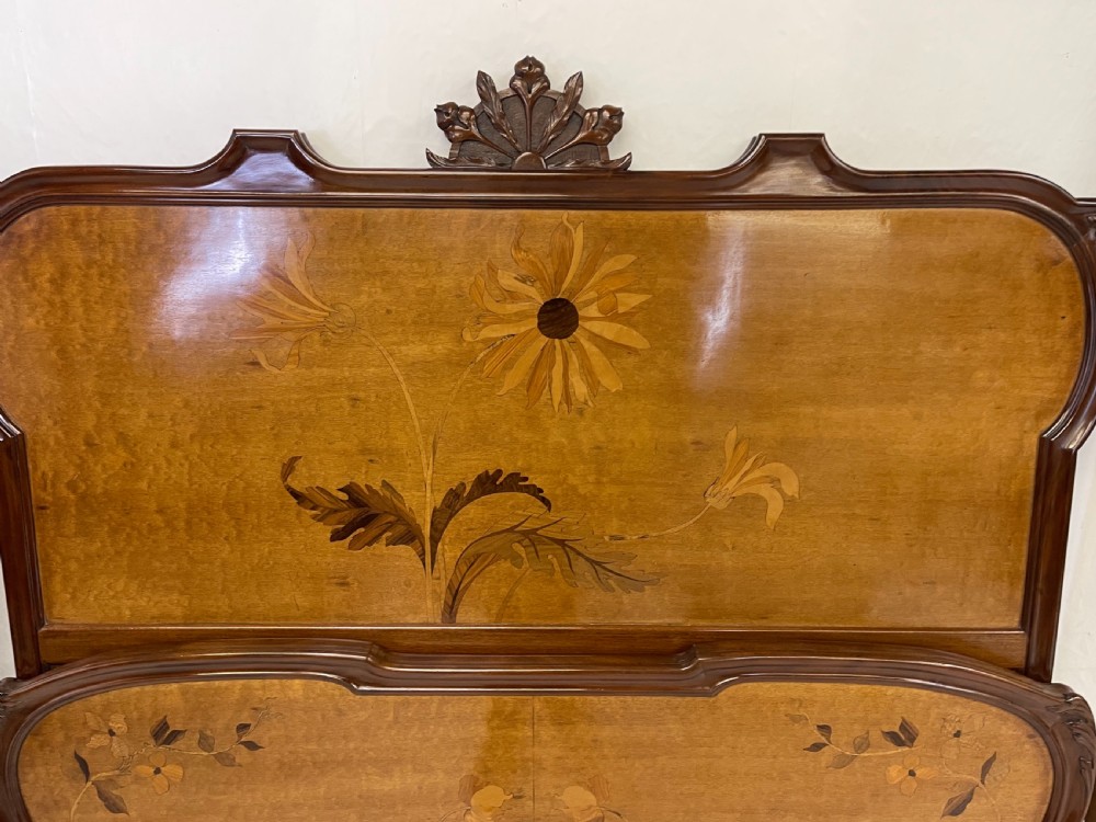 An Art Nouveau wooden bed frame featuring floral marquetry inlay on the headboard and footboard with carved organic scrollwork. View V