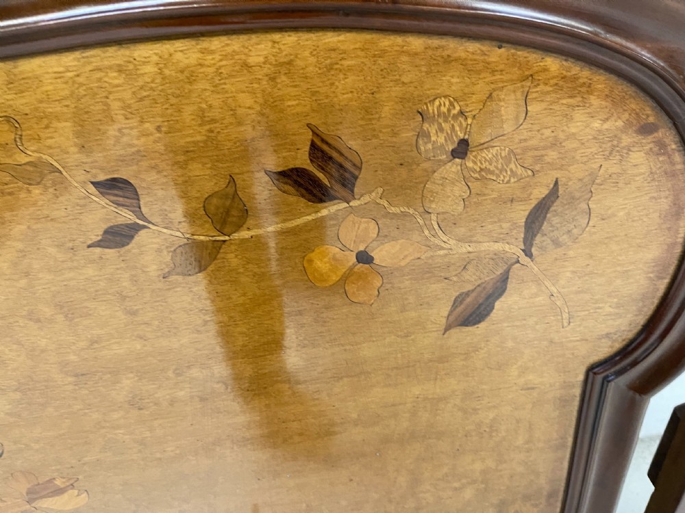 An Art Nouveau wooden bed frame featuring floral marquetry inlay on the headboard and footboard with carved organic scrollwork. View XIV