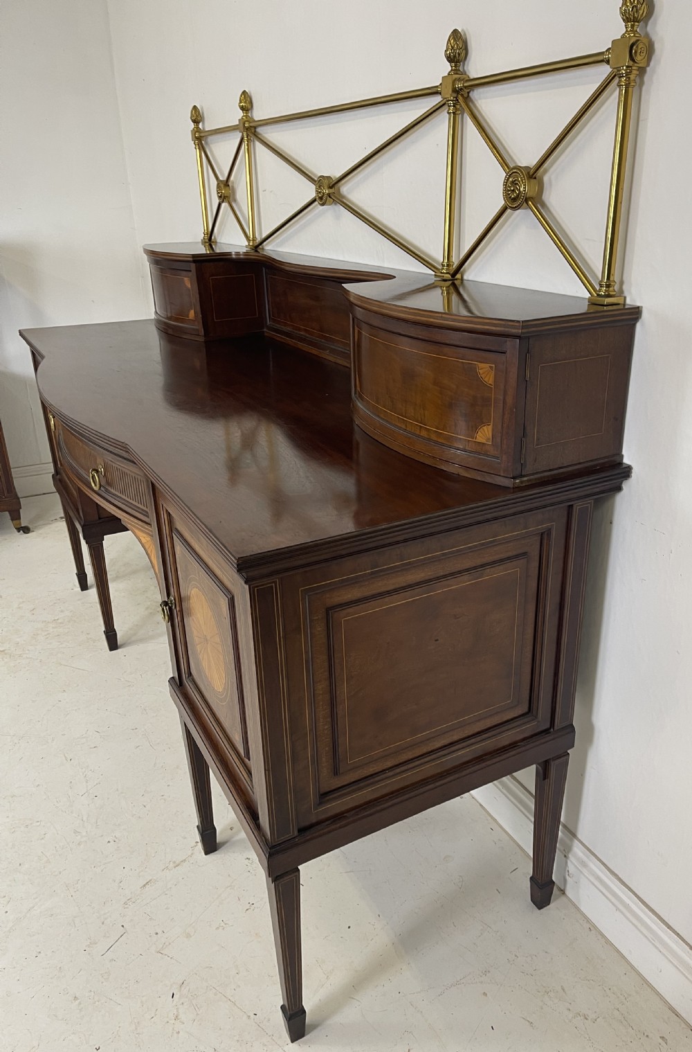 An inlaid mahogany sideboard and matching serving table featuring brass gallery rails and satinwood fan marquetry. View XVI