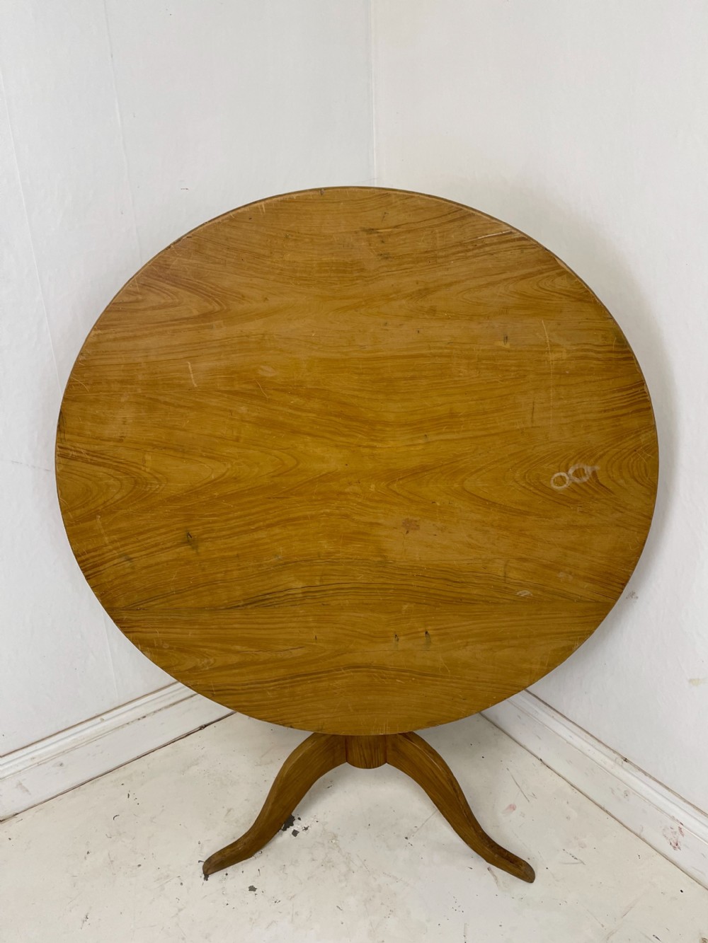 A circular pine tilt-top table presented in its raised vertical position showing its natural timber grain and tripod base. View II