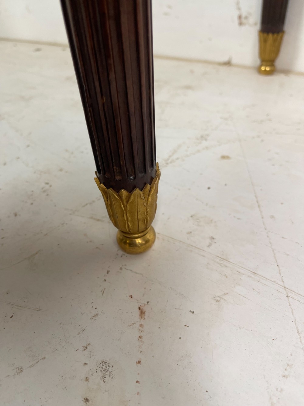 A polished dark mahogany fold-over card table featuring tapered fluted legs topped with gilt bronze acanthus collars. View IV