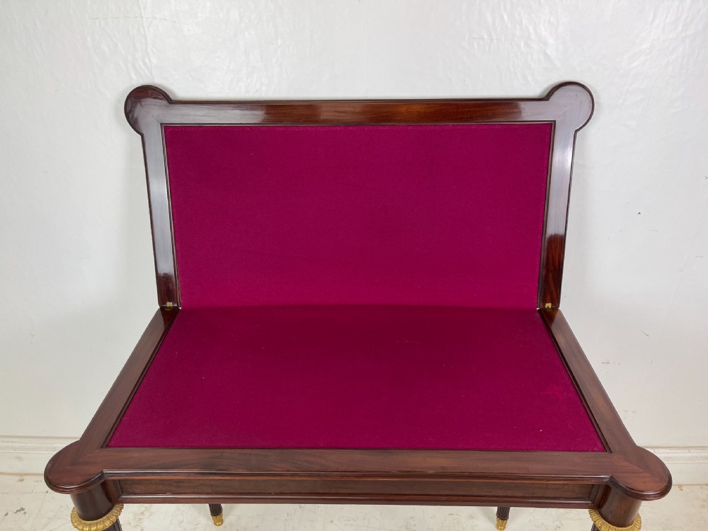 A polished dark mahogany fold-over card table featuring tapered fluted legs topped with gilt bronze acanthus collars. View VII