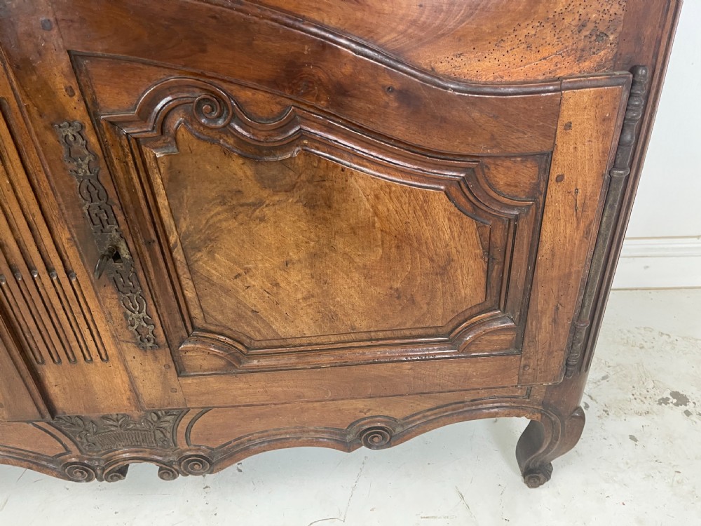 An antique French provincial walnut buffet deux corps featuring two upper panelled doors under a shaped cornice, two lower drawers, and carved cupboard doors resting on short cabriole feet. View XI