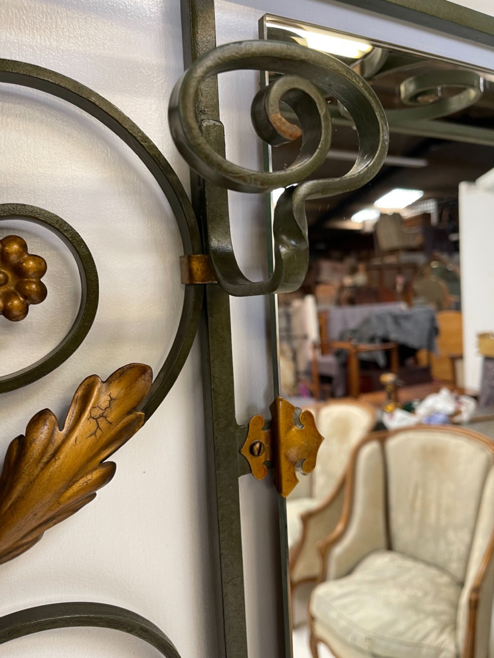 A tall French Art Deco wrought iron hall stand featuring symmetrical scrollwork with gold leaf accents, a central full-length mirror, multiple hooks, and umbrella drip trays. View V