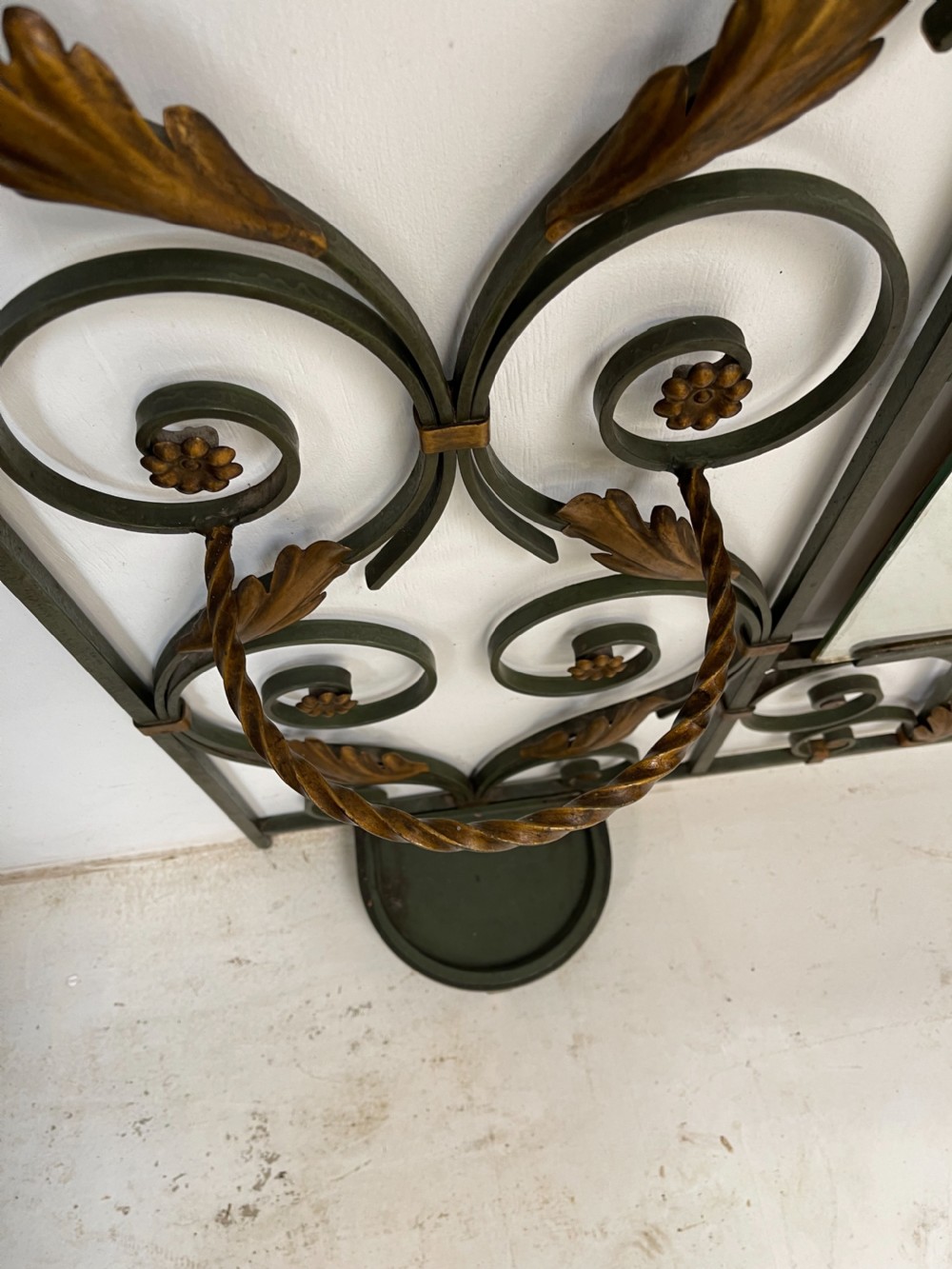 A tall French Art Deco wrought iron hall stand featuring symmetrical scrollwork with gold leaf accents, a central full-length mirror, multiple hooks, and umbrella drip trays. View VII
