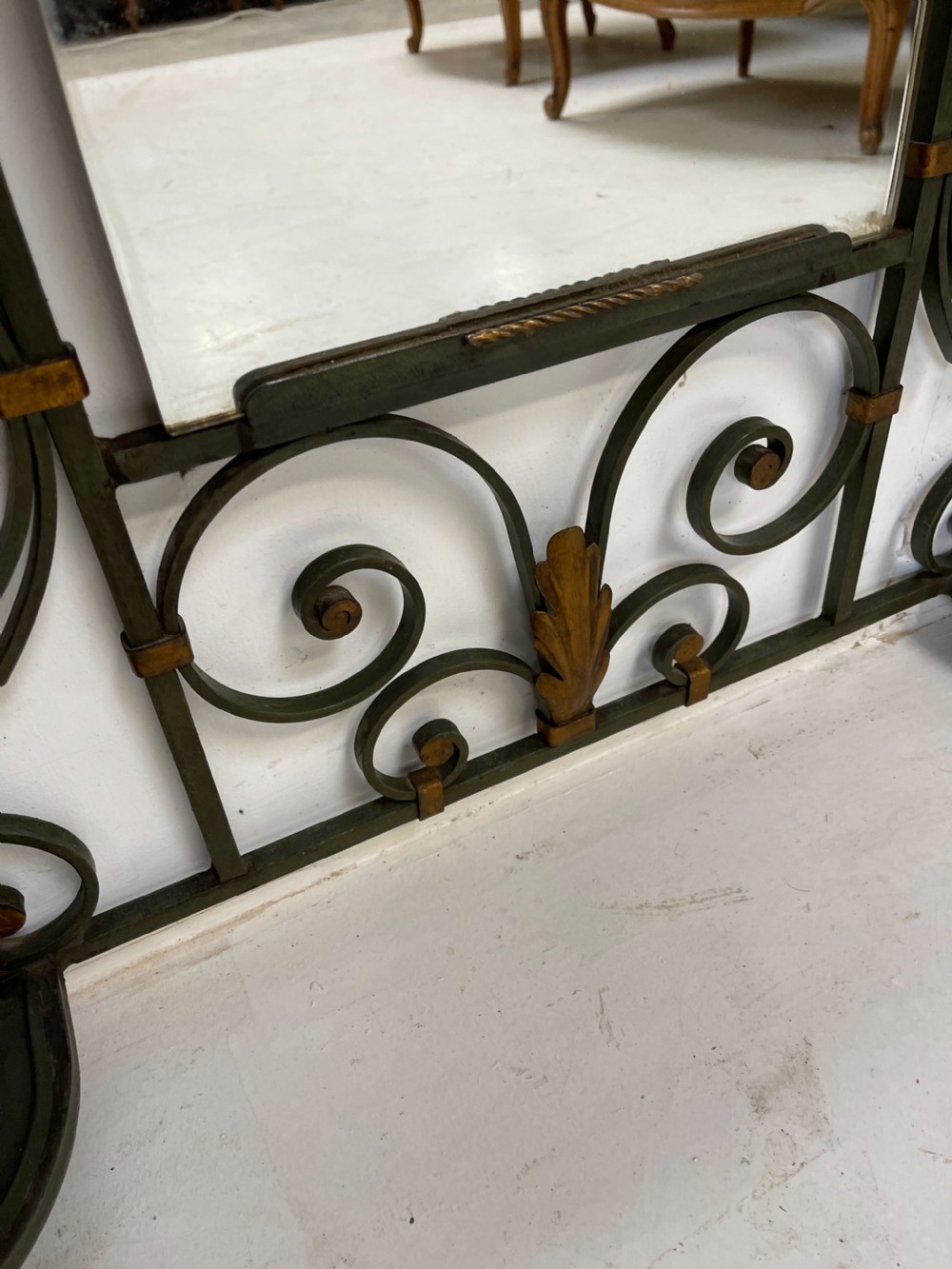 A tall French Art Deco wrought iron hall stand featuring symmetrical scrollwork with gold leaf accents, a central full-length mirror, multiple hooks, and umbrella drip trays. View X