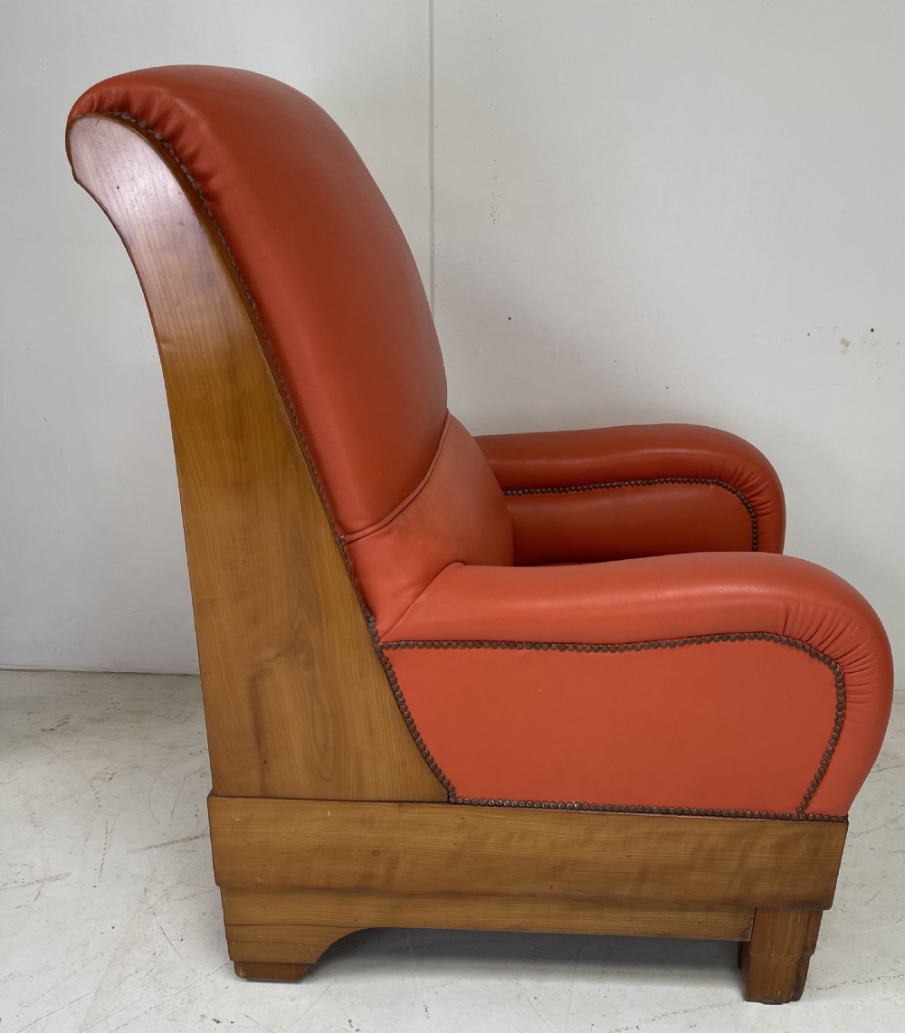 A pair of Art Deco high-backed armchairs upholstered in terracotta orange leather with dark wooden frames and bases. View II