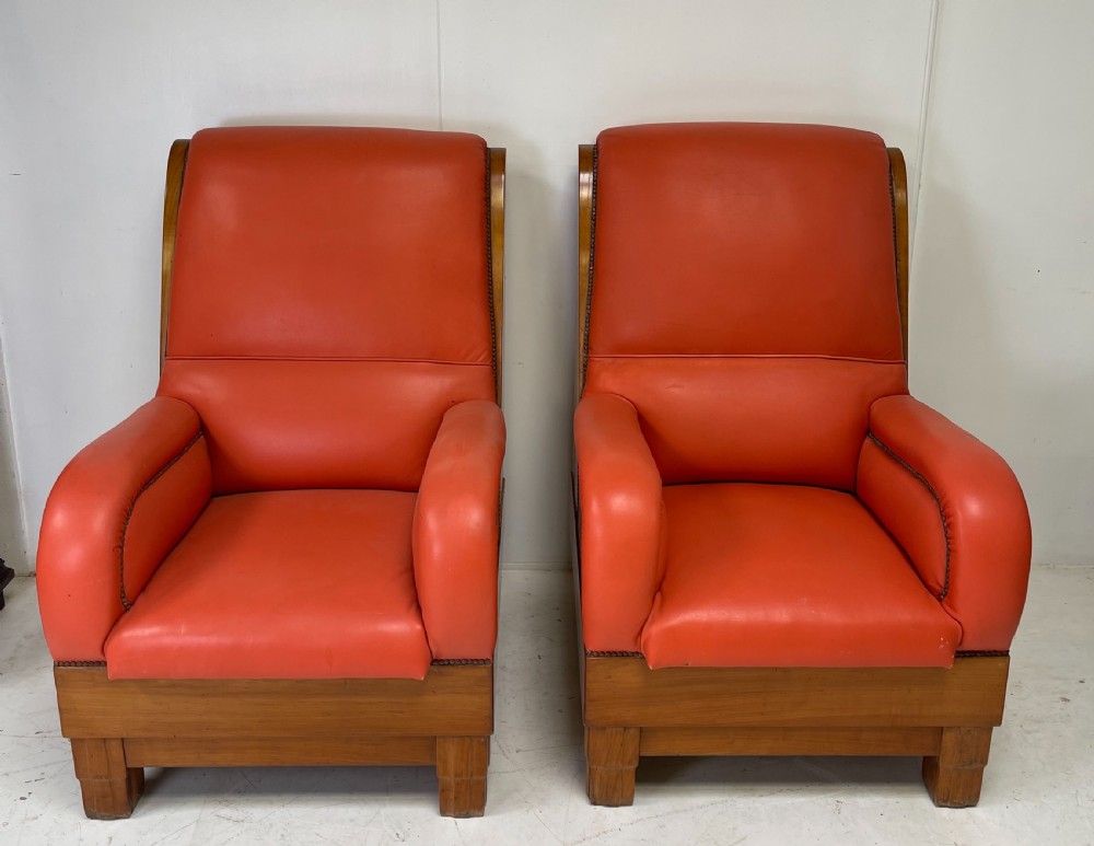 A pair of Art Deco high-backed armchairs upholstered in terracotta orange leather with dark wooden frames and bases. View VIII