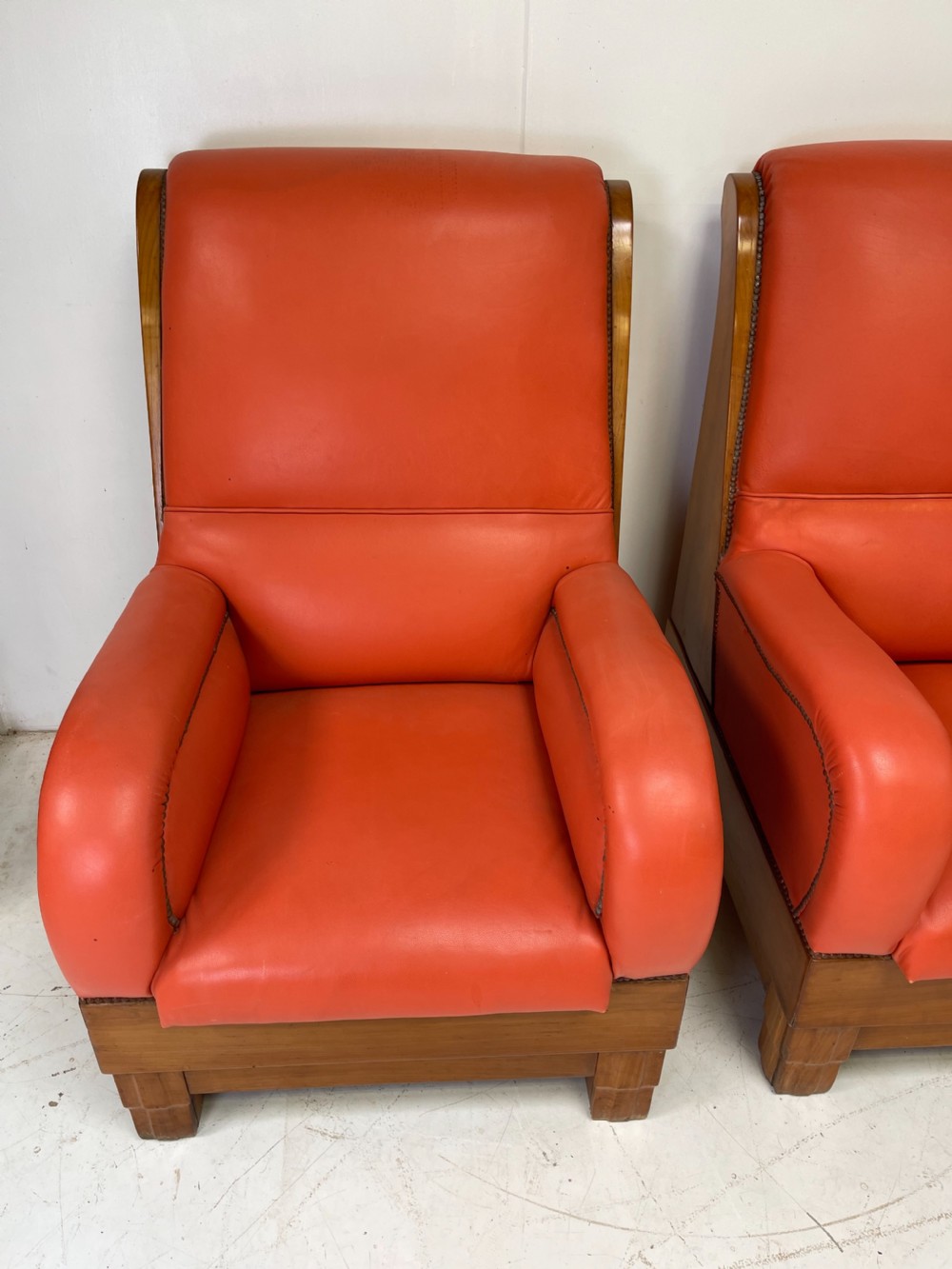 A pair of Art Deco high-backed armchairs upholstered in terracotta orange leather with dark wooden frames and bases. View IX