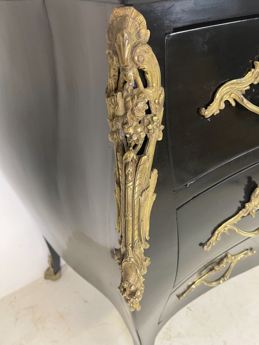 A pair of black ebonised Louis XV style bombee commodes featuring pink marble tops and ornate gilt metal mounts. View III