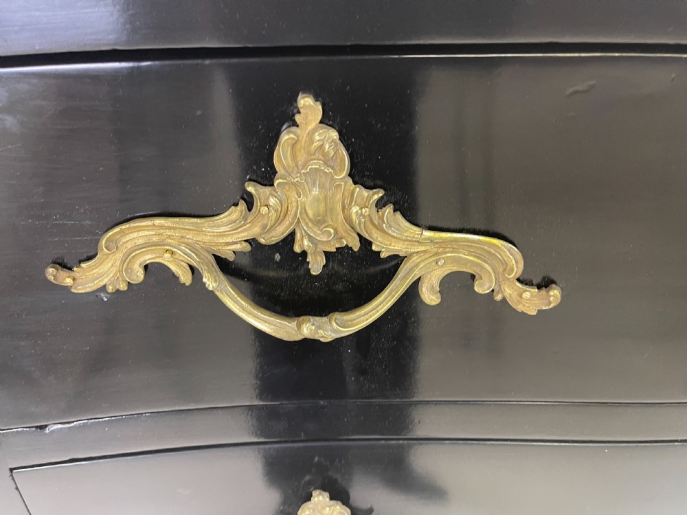 A pair of black ebonised Louis XV style bombee commodes featuring pink marble tops and ornate gilt metal mounts. View VII