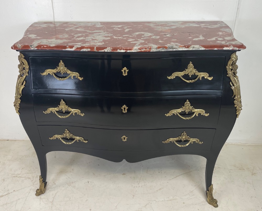 A pair of black ebonised Louis XV style bombee commodes featuring pink marble tops and ornate gilt metal mounts. View IX