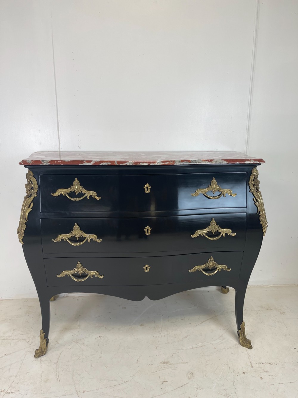 A pair of black ebonised Louis XV style bombee commodes featuring pink marble tops and ornate gilt metal mounts. View X