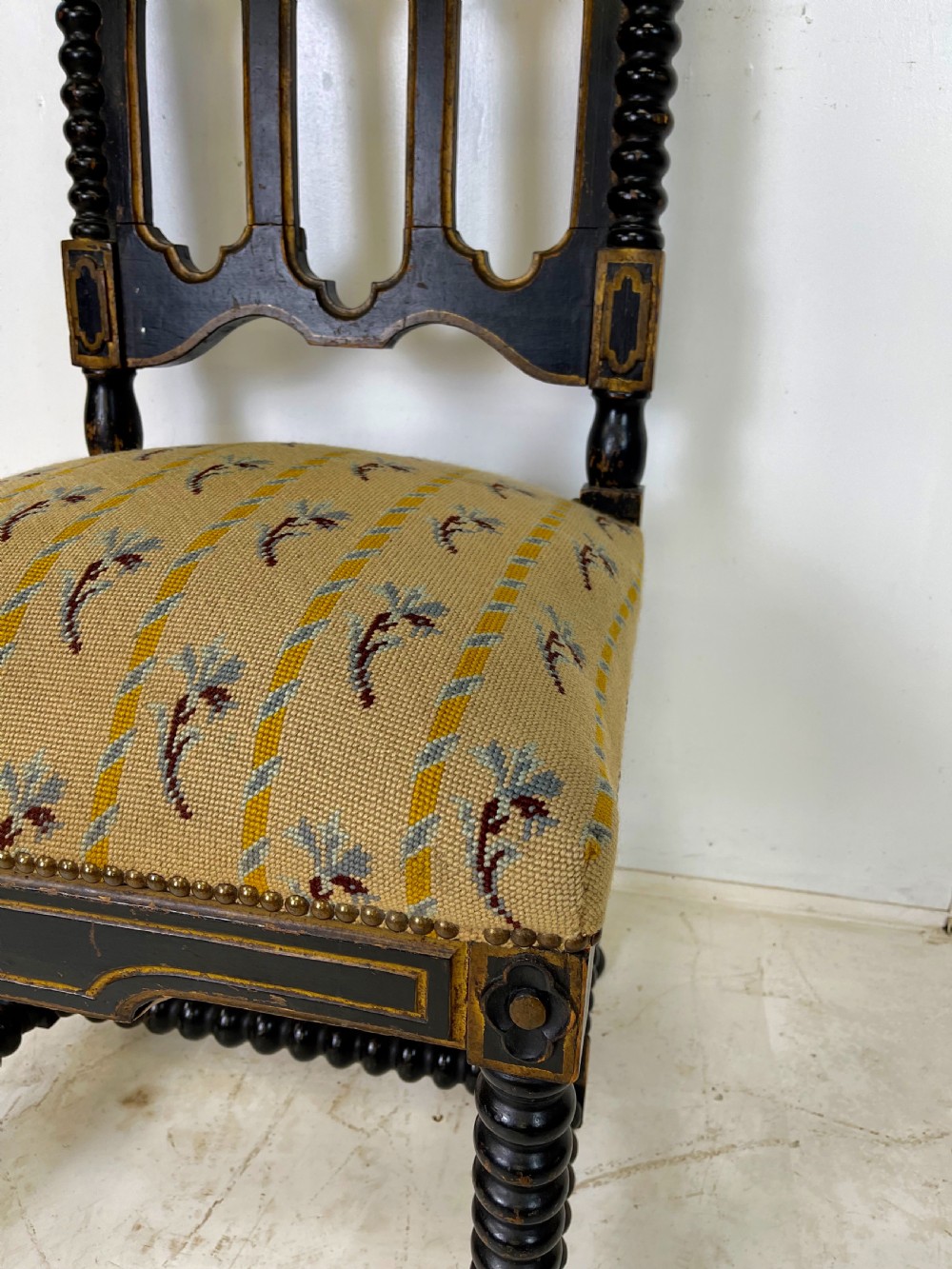 A Victorian Gothic Revival side chair featuring an ebonised frame with lancet arch tracery, bobbin turned legs, and patterned cream upholstery with brass stud details. View II