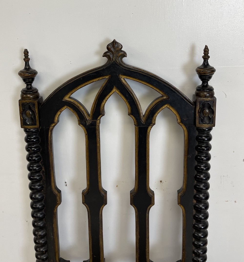 A Victorian Gothic Revival side chair featuring an ebonised frame with lancet arch tracery, bobbin turned legs, and patterned cream upholstery with brass stud details. View IX