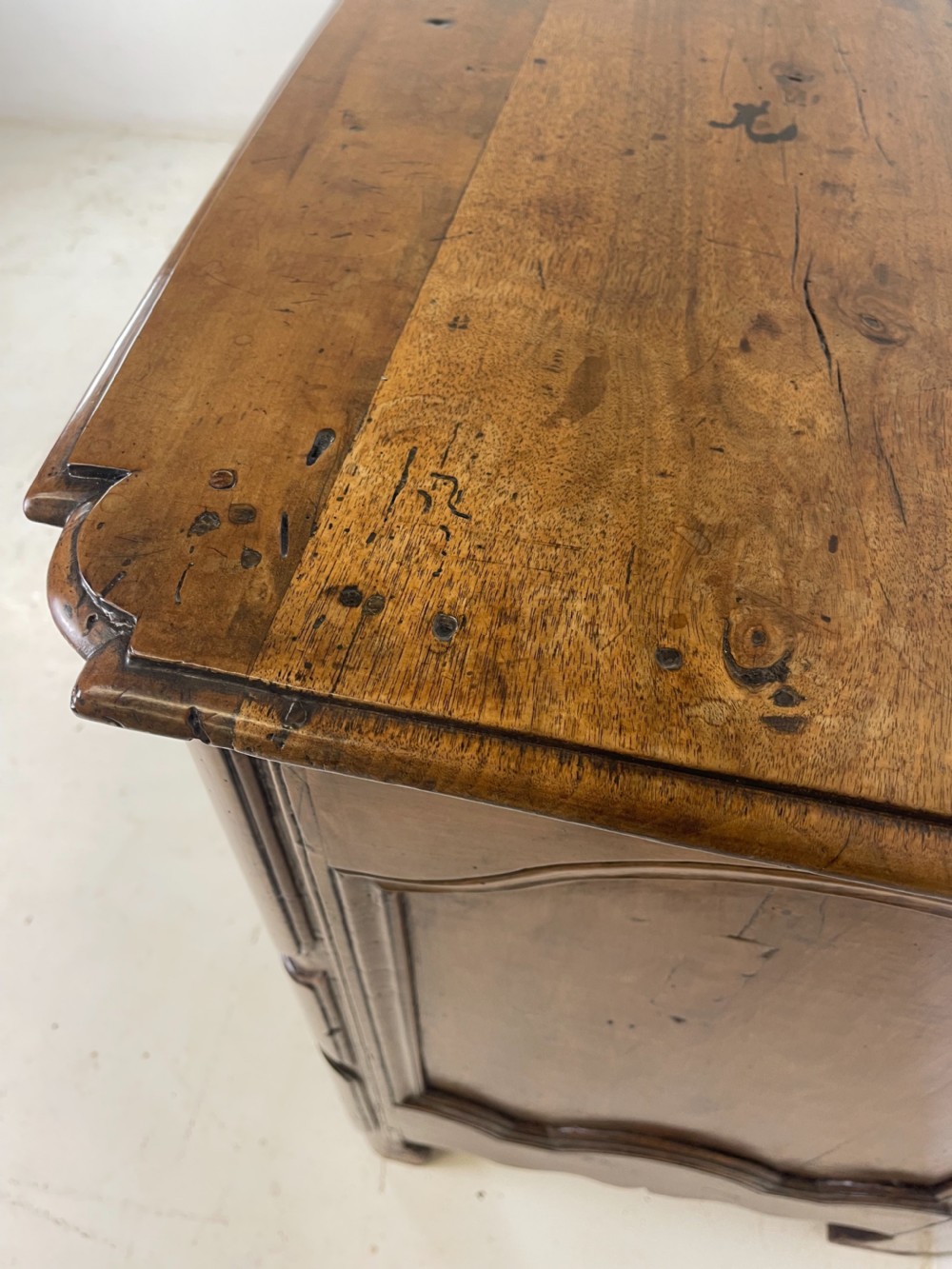 An eighteenth-century French provincial fruitwood commode featuring three wide drawers with moulded panel fronts, ornate brass rococo handles, and short curved legs. View X
