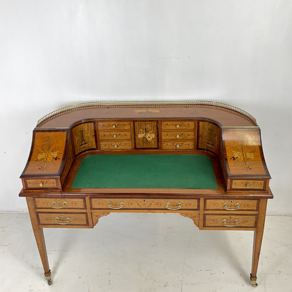 An Edwardian satinwood Carlton House desk with floral marquetry inlay, a green leather writing surface, multiple drawers, and a brass gallery top. View II