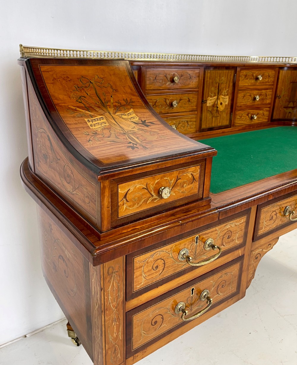 An Edwardian satinwood Carlton House desk with floral marquetry inlay, a green leather writing surface, multiple drawers, and a brass gallery top. View III