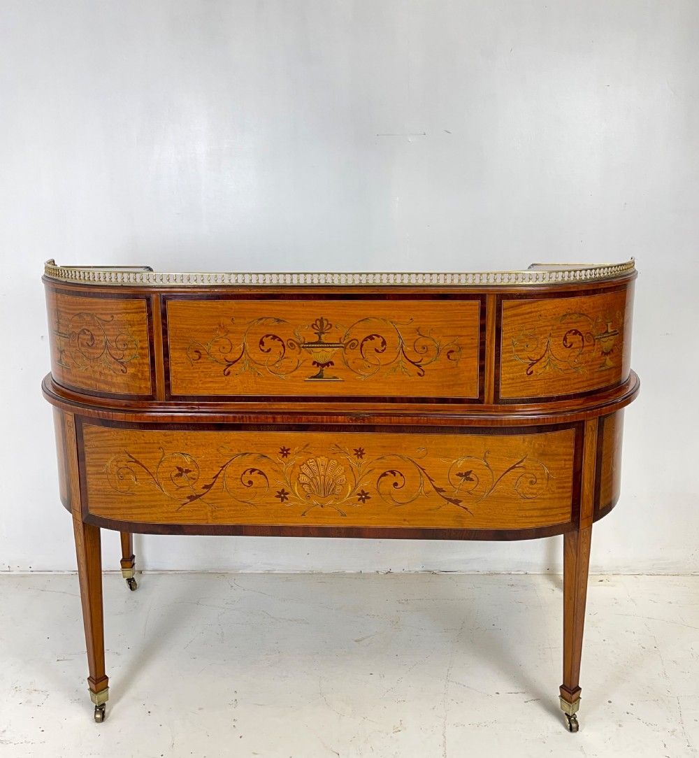 An Edwardian satinwood Carlton House desk with floral marquetry inlay, a green leather writing surface, multiple drawers, and a brass gallery top. View XII