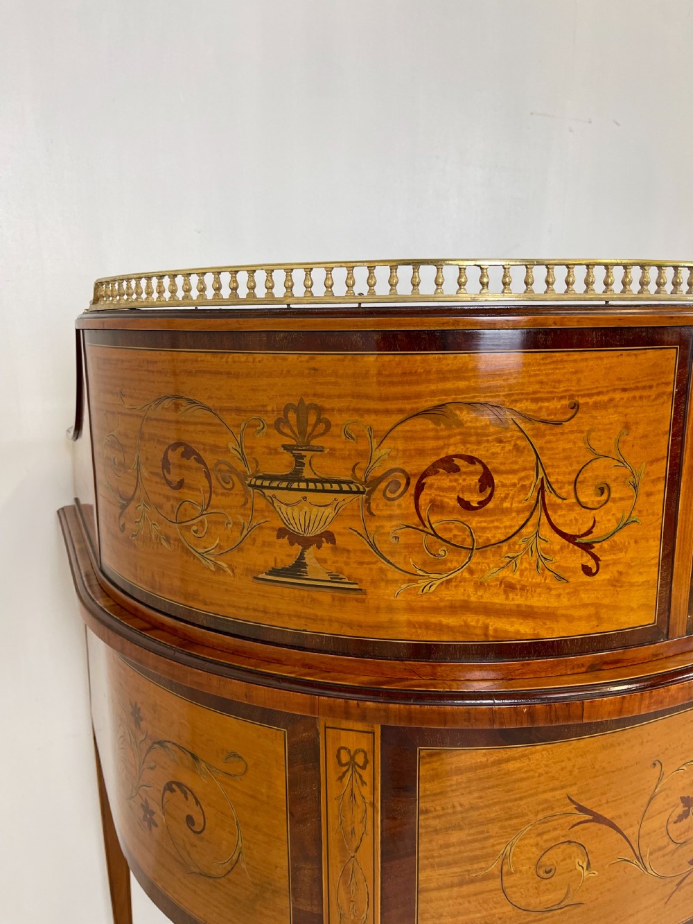An Edwardian satinwood Carlton House desk with floral marquetry inlay, a green leather writing surface, multiple drawers, and a brass gallery top. View XVIII