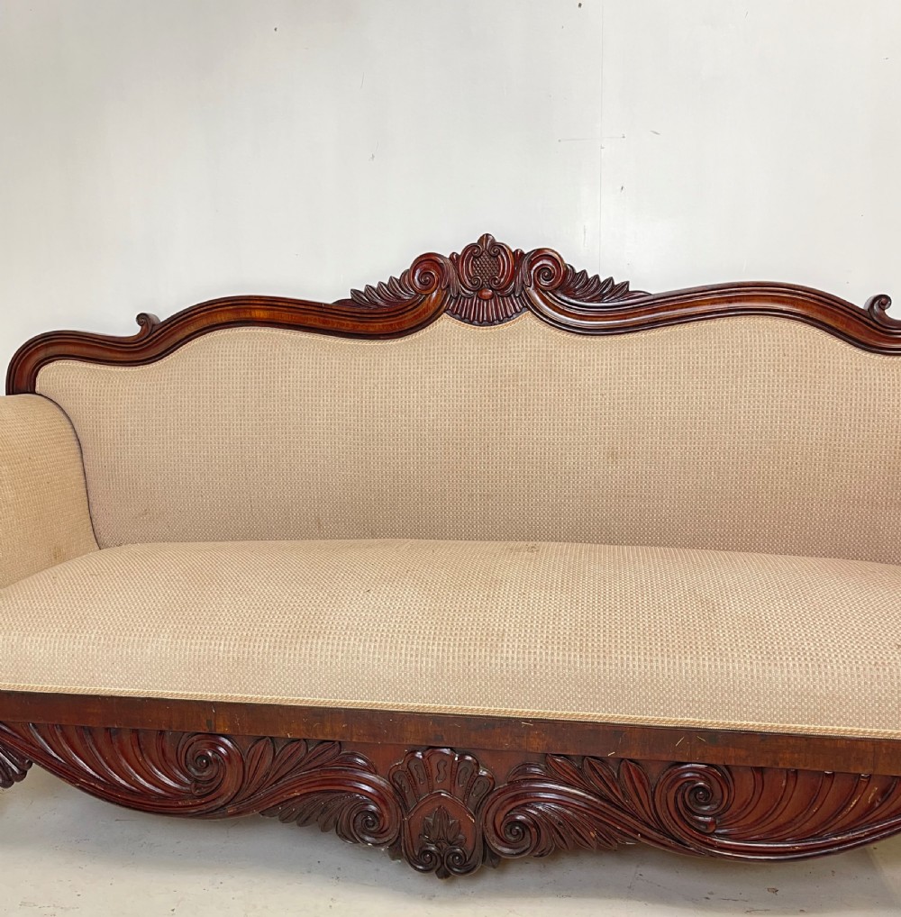 A large antique mahogany sofa featuring intricately hand-carved acanthus scrollwork along the apron and arms, upholstered in a light cream textured fabric. View III