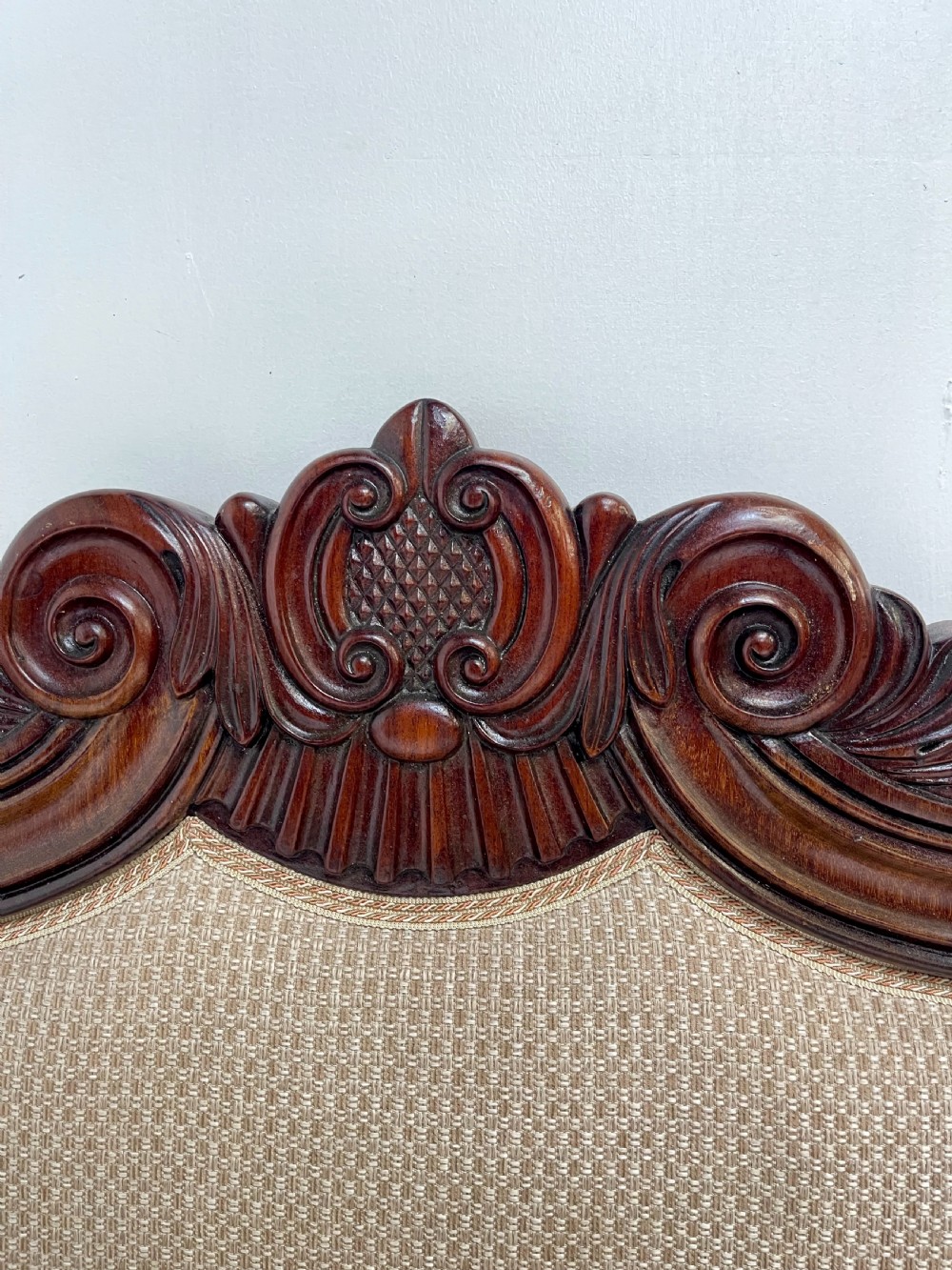 A large antique mahogany sofa featuring intricately hand-carved acanthus scrollwork along the apron and arms, upholstered in a light cream textured fabric. View IV