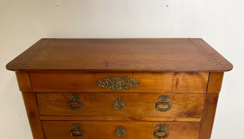 A tall French cherrywood semainier featuring seven drawers with brass drop handles and decorative keyhole escutcheons. View V