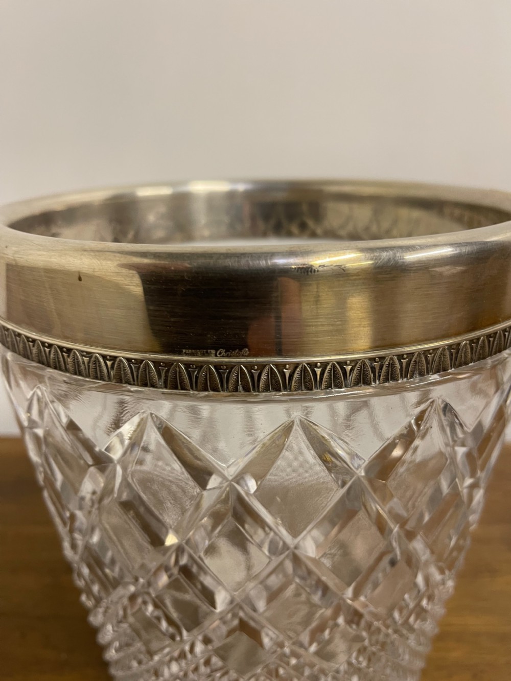 A clear cut glass ice bucket featuring diamond geometric facet patterns with a silver-plated rim and twin side handles. View VII