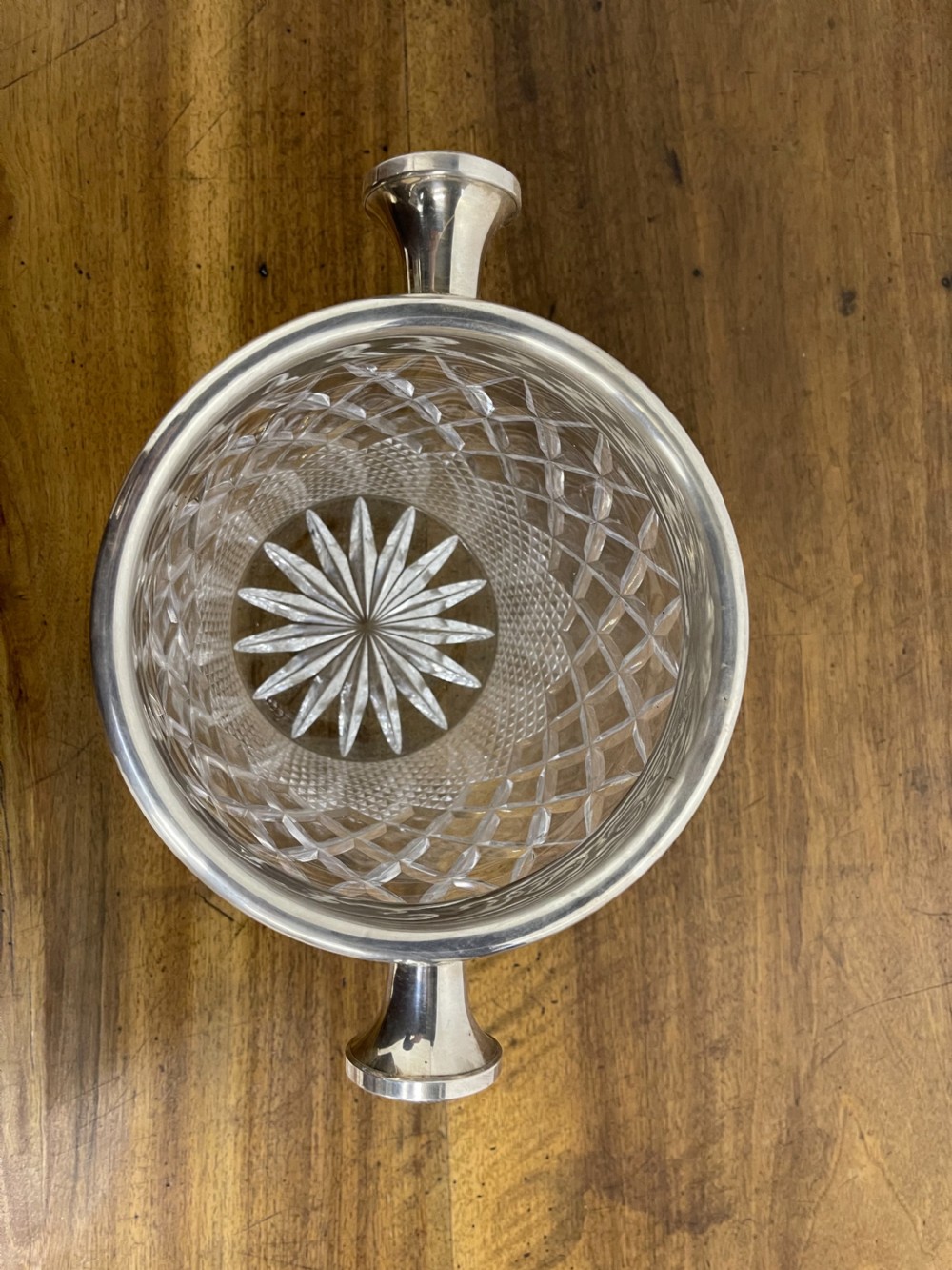 A clear cut glass ice bucket featuring diamond geometric facet patterns with a silver-plated rim and twin side handles. View IX